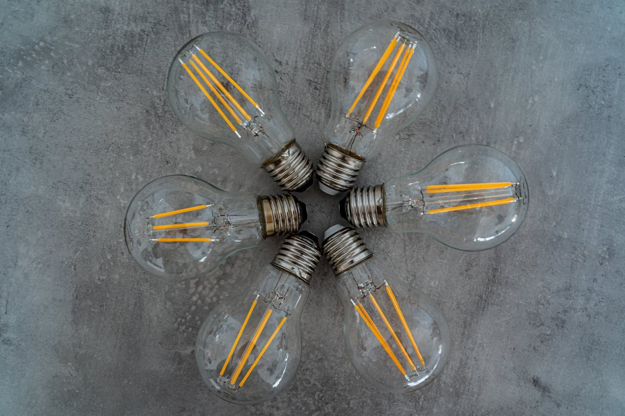 Artistic arrangement of Edison light bulbs in star pattern on concrete background.